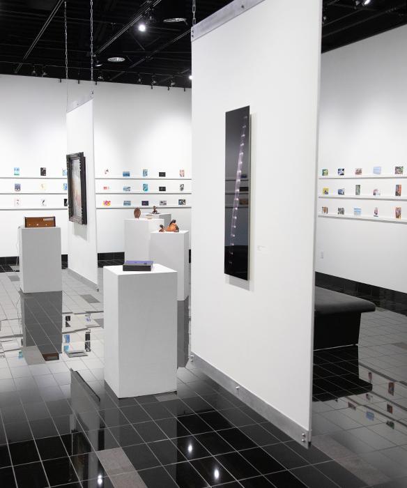 Gallery with white walls displaying postcard-sized art pieces