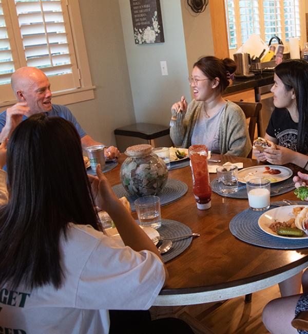 A host family sitting around a dinner table with international students