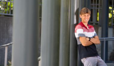 SPSCC student-athlete Joshua Coetzee leaning against a gray pillar