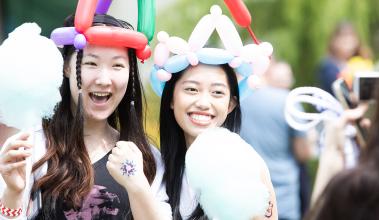 Two students wearing balloon crowns and holding cotton candy on paper cones
