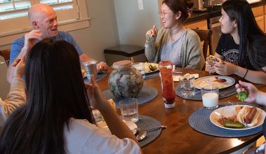 A host family sitting around a dinner table with international students