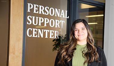 Person standing in front of a window with a sign that reads "Personal Support Center"