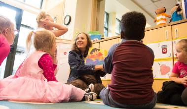 Teacher reads a book to a room of young children
