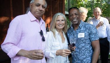 Four people looking at the camera smiling. Holding Drinks.