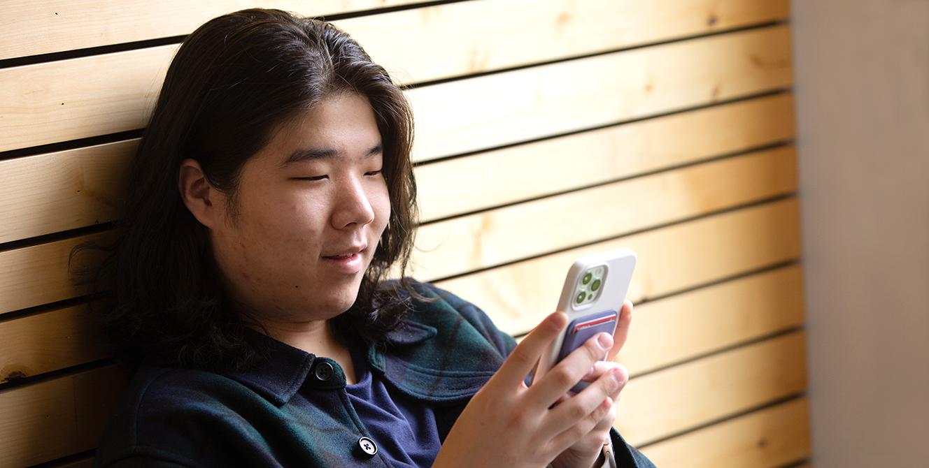 A student looking at their phone and smiling