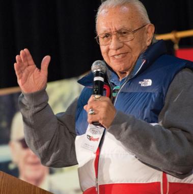Billy Frank Jr. profile, smiling while holding a microphone with hand in motion