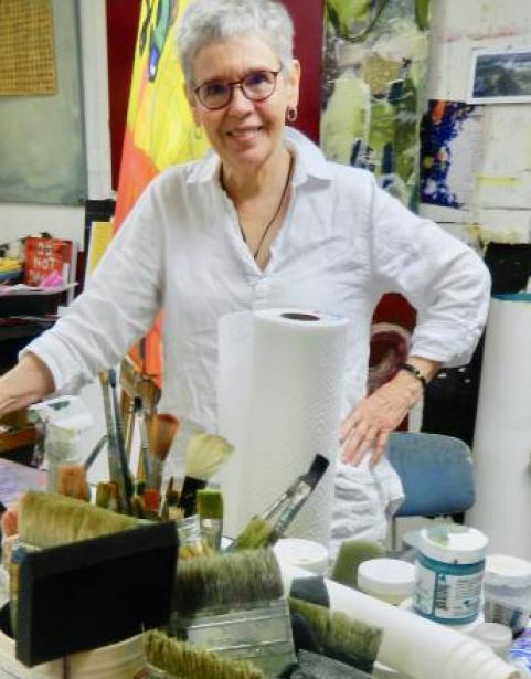 Portrait of artist Becky Knold behind art supplies