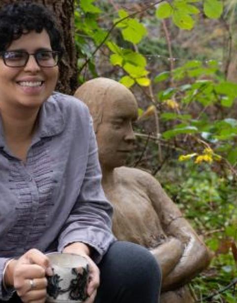 Photo of Aisha Harrison with a wood carving person in the background