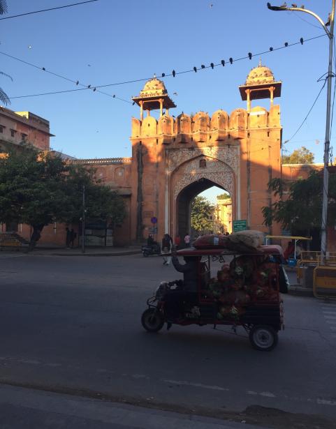 A street with a car driving across next to a monument in Jaipur, India