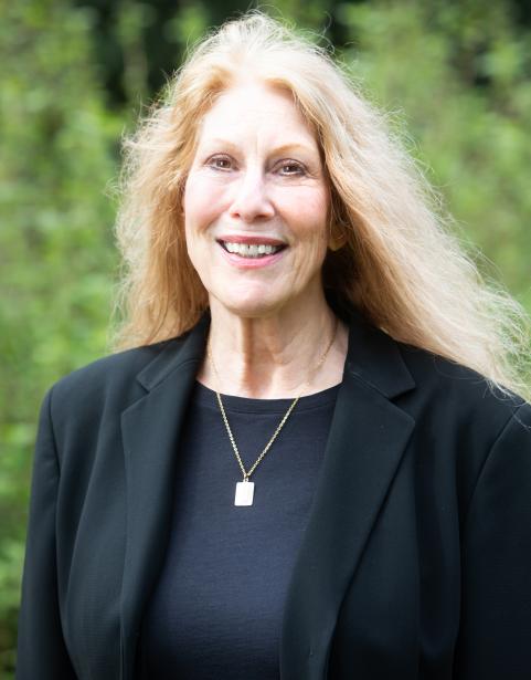 English Professor Nancy Miller in front of greenery