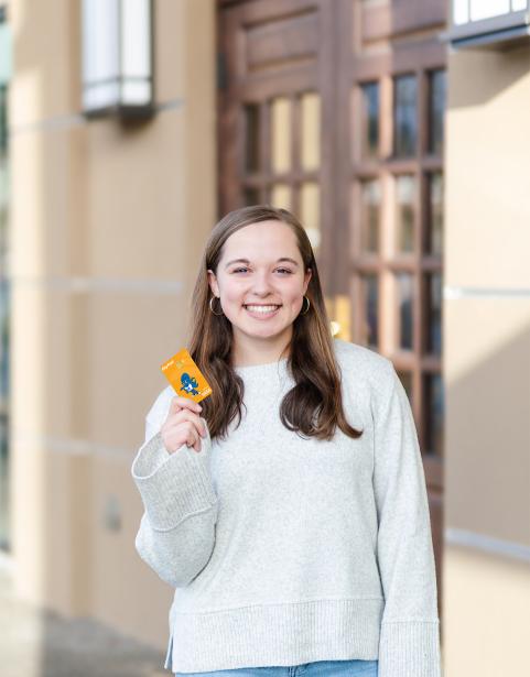 A young woman holding an SPSCC-branded debit card