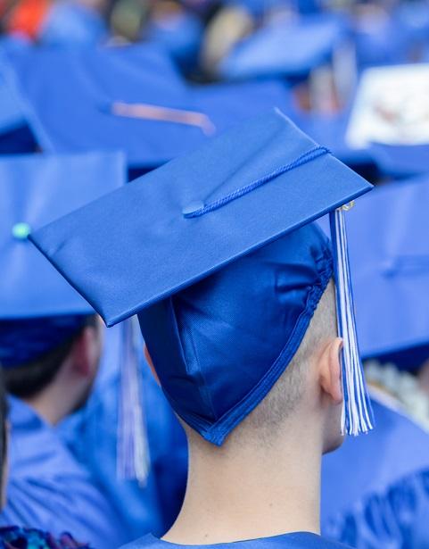 close up of blue graduation cap on student head from behind