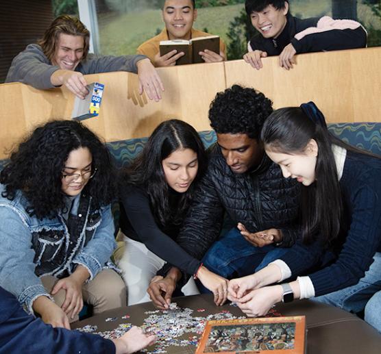 Students gathered around a table putting together a puzzle