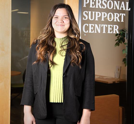 A person standing in front of a sign that reads "Personal Support Center"