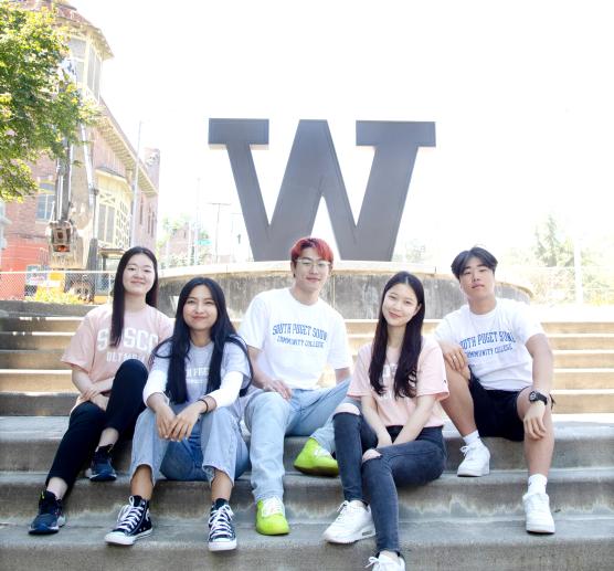 Students sitting in front of University of Washington Tacoma's "W" sign