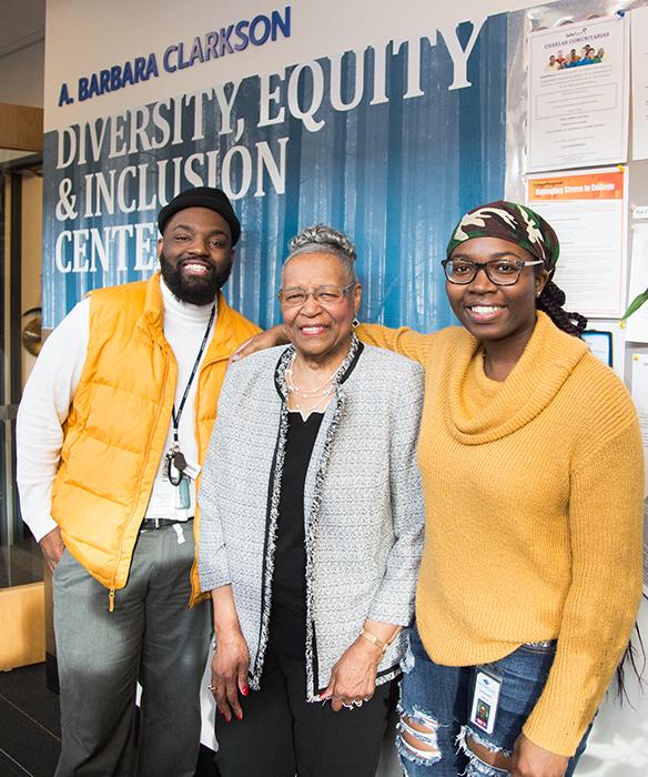 Three people standing next to a white and blue wall with text that reads "A. Barbara Clarkson Diversity, Equity & Inclusion Center"