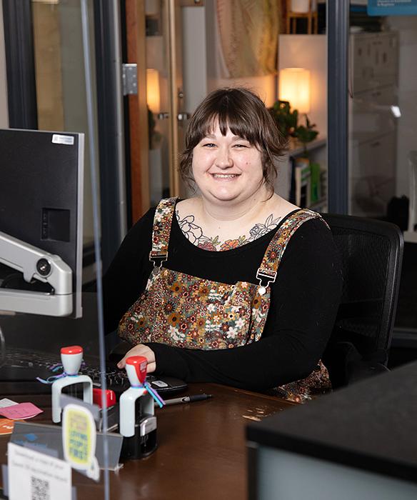 One Stop support person smiles at a desk in front of a computer