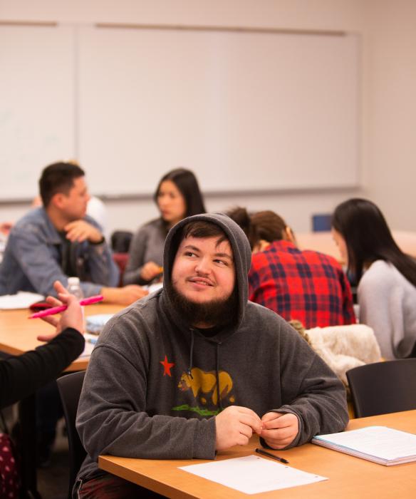 Student at desk smiles and looks up