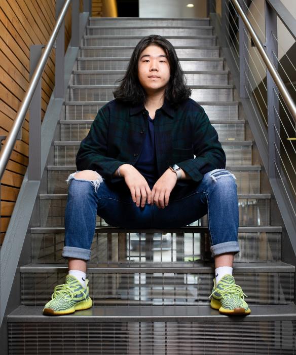 Student looks at camera sitting on modern metal stairs inside a building