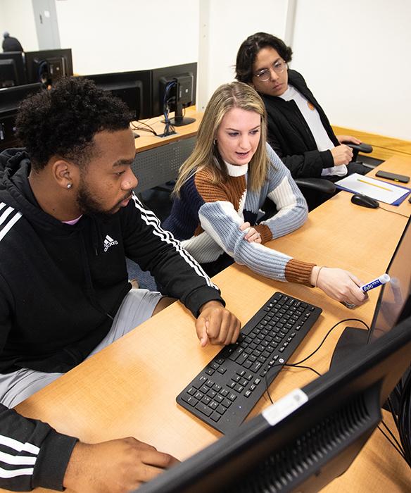 Instructor with two students points at a computer