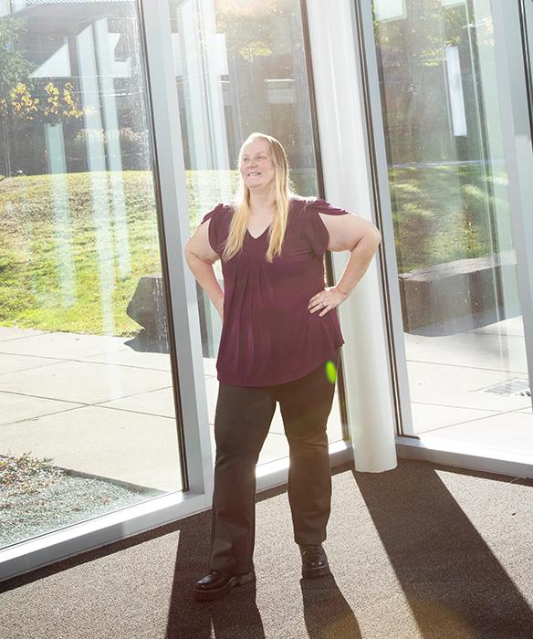 Student smiles in front of glass architecture with golden evening lighting