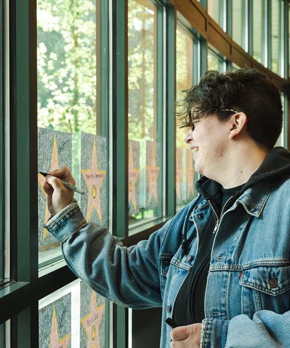 Employee writes on star graphic on window