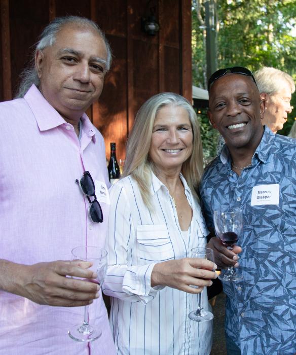Four people looking at the camera smiling. Holding Drinks.