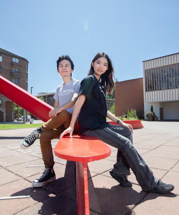Two students sitting on a red sculpture on Western Washington University's campus