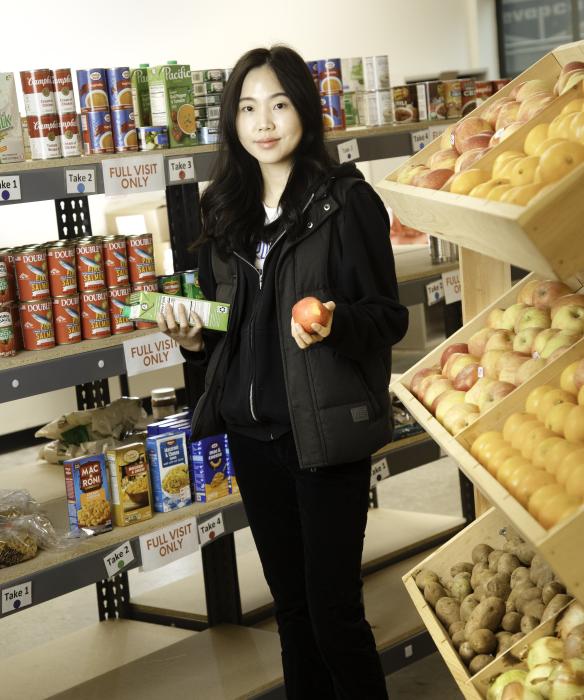 A student worker holds a piece of fruit and box of soy milk in food pantry