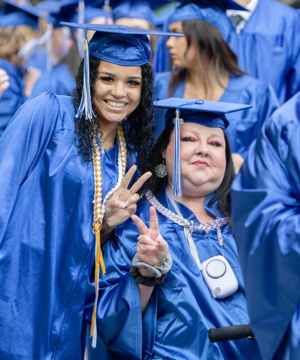 Two students smiling in cap & gown at graduation