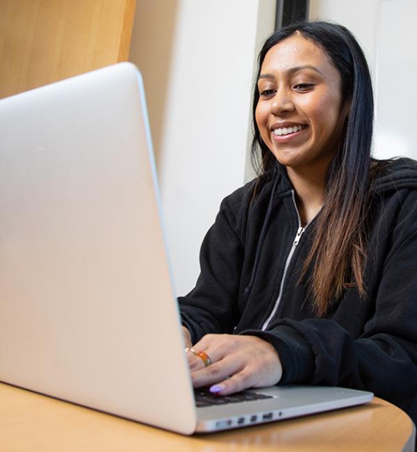 Student smiles while using laptop