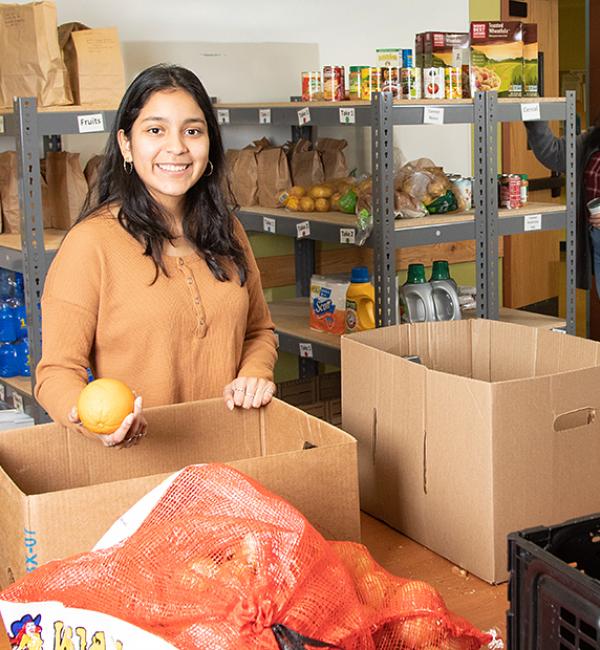 Student holding an orange in the Food Pantry