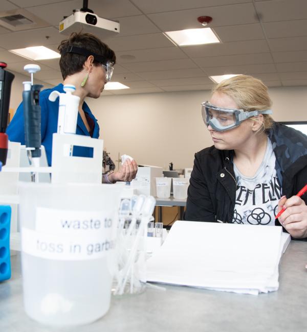 Two students in science of brewing classroom with safety goggles