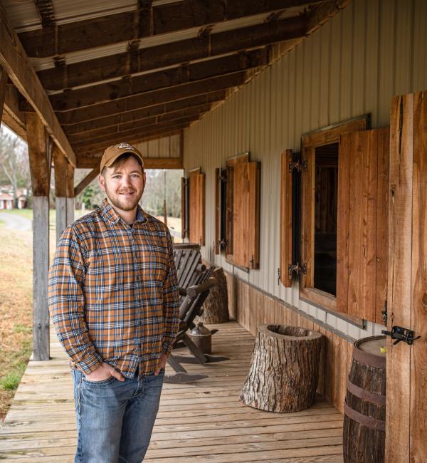 Luke stands on deck of wood shed on his farm in Kentucky