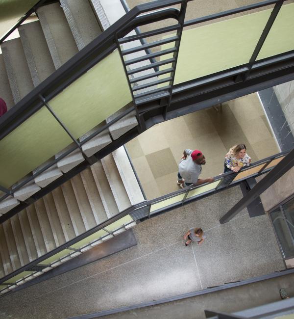 Two people looking up a stairwell in SPSCC's Building 22 as another person walks down