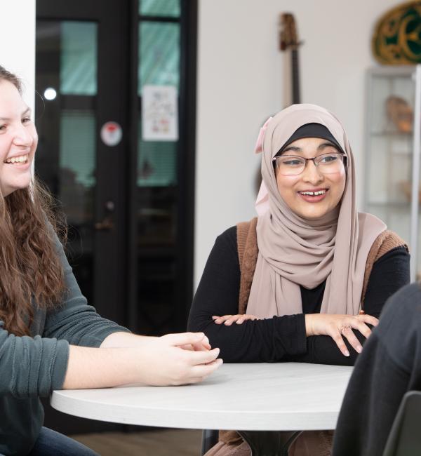 Group of students discuss while sitting at a table in the Belonging Center