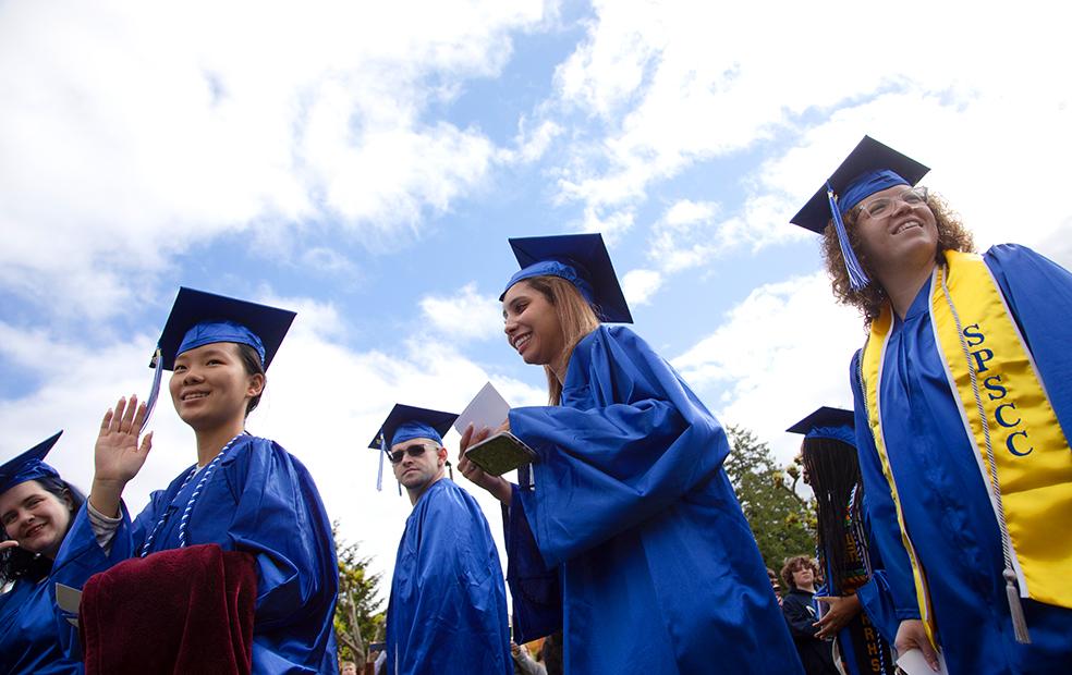 Students dressed in blue graduation caps and gowns