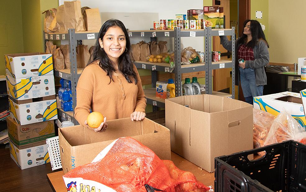 Student holding an orange in the Food Pantry