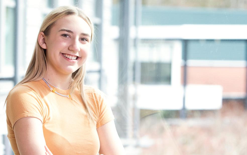 Student smiles looking at camera in light orange shirt
