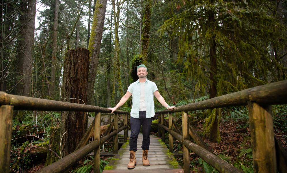Photo of Alec Anderson standing on a bridge in the middle of the forest