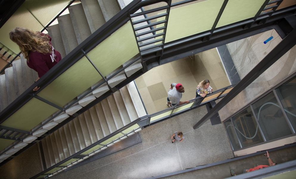 Two people looking up a stairwell in SPSCC's Building 22 as another person walks down