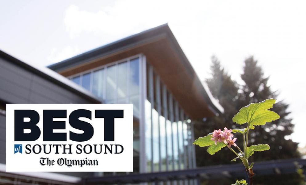 A flower blooming in front of SPSCC's Building 21 with a badge that reads, "Best of South Sound, The Olympian"