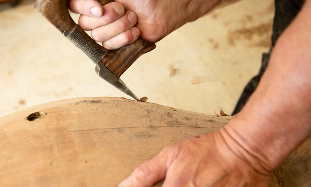 A close up of an artist's hands carving wood