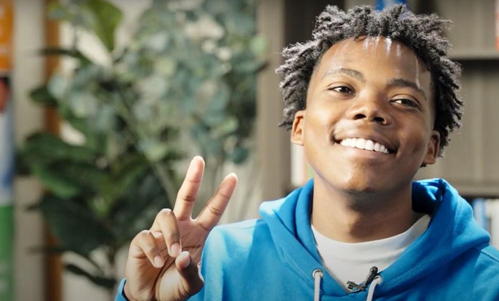 An Entrepreneur Academy student smiling and holding up a peace sign